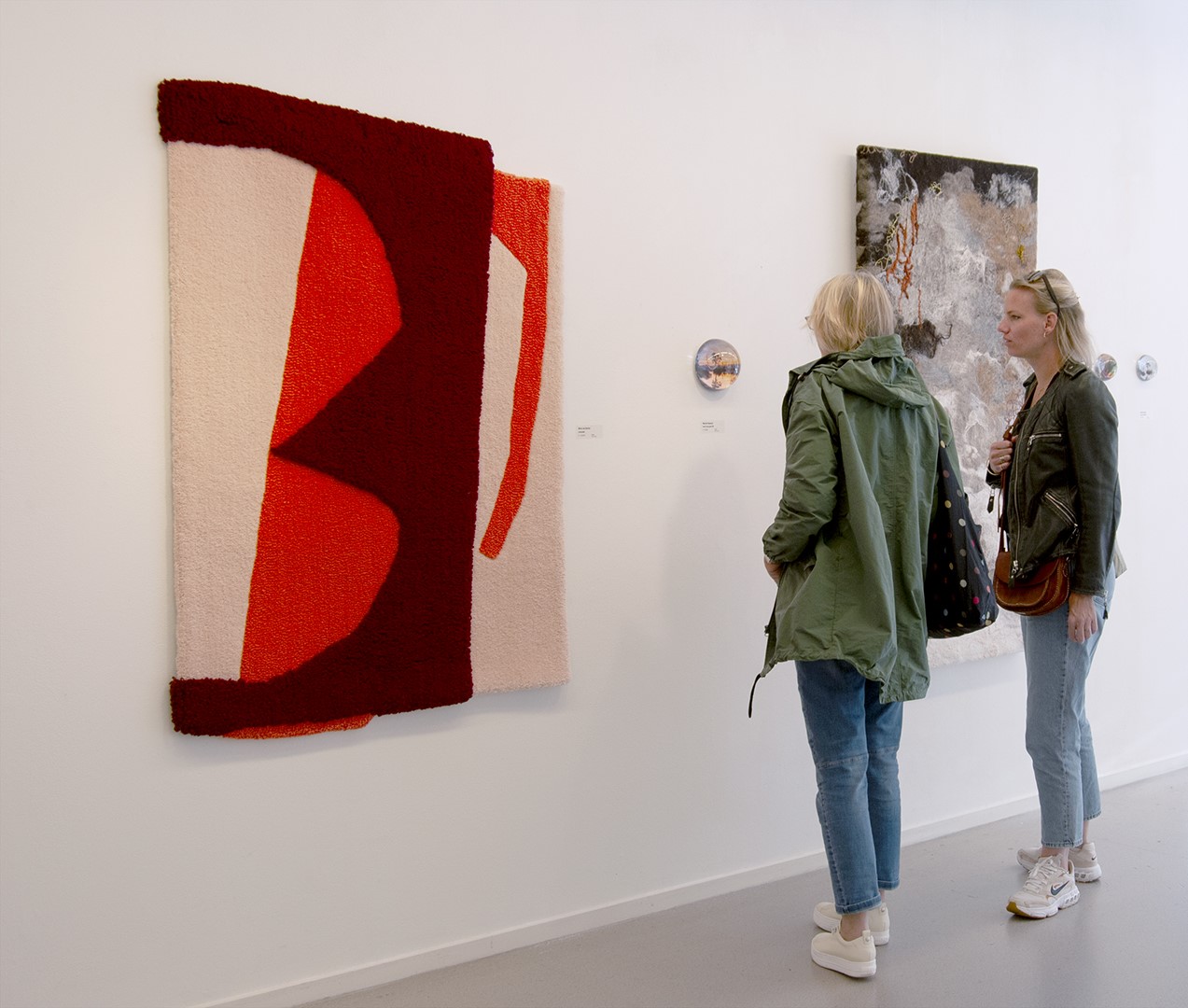 Bezoekers bekijken werken van de tentoonstelling 'De natuur in textiel en glas' in de galerie van Kunst Centrum Haarlem